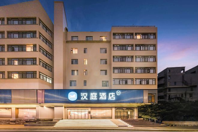 A hotel building with multiple floors, a prominent entrance with steps, and a signboard.