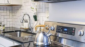 Una cucina moderna con piano cottura in acciaio inossidabile, forno a microonde e bollitore sul fornello.