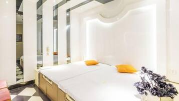 Una habitación de hotel moderna con una cama grande, una mesita de noche y un espejo.