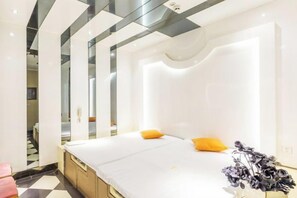 Une chambre d’hôtel moderne avec un grand lit, une table de chevet et un miroir.