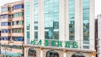 A multi-story building with a prominent green sign on the ground floor.