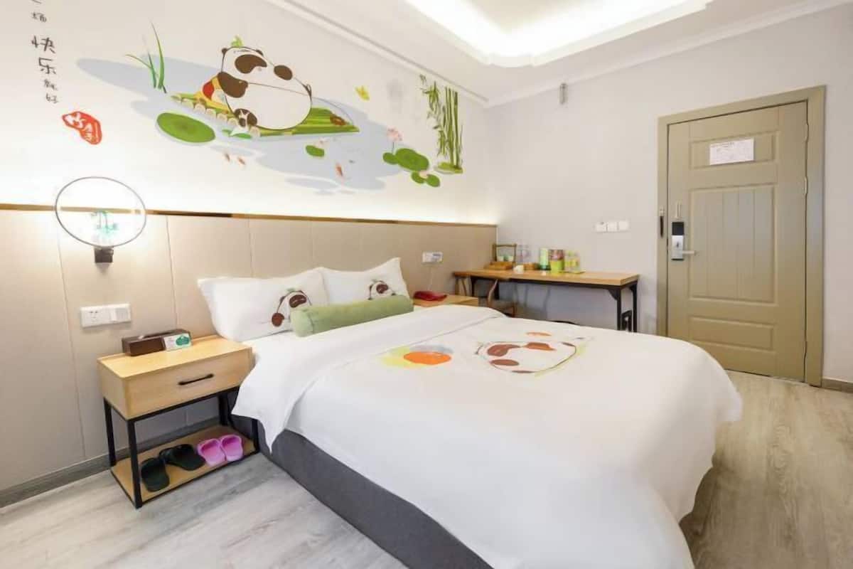 Una habitación de hotel con una cama, una mesita de noche, una pequeña mesa y una puerta.