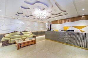 A hotel lobby with a reception desk, a sofa, and a coffee table. - Zhufangzi Cinema Hotel (Anyue Beimenkou) (Anyue)
