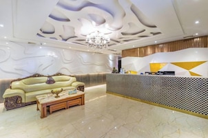 Un vestíbulo de hotel con una recepción, un sofá y una mesa de centro.