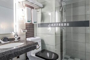 A modern bathroom with a granite countertop sink, a toilet, and a glass shower enclosure.