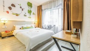 Ein Hotelzimmer mit Bett, Nachttisch, Lampe und einem Fenster mit Vorhängen.