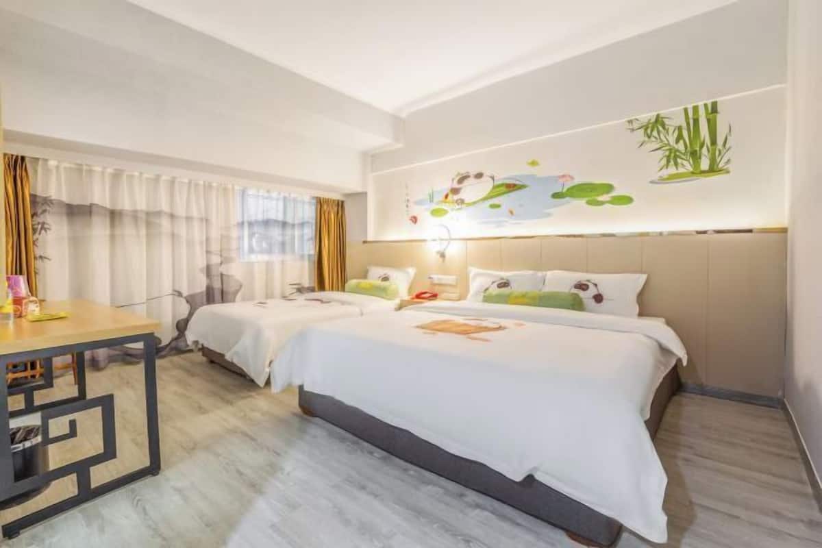 Habitación de hotel con dos camas, un escritorio y una pared con un mural de temática natural.