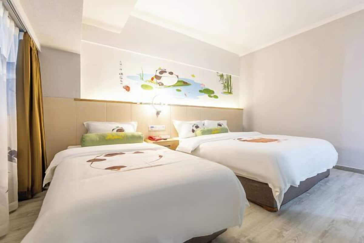 Una habitación de hotel con dos camas, un mural en la pared y una mesita de noche con lámpara.