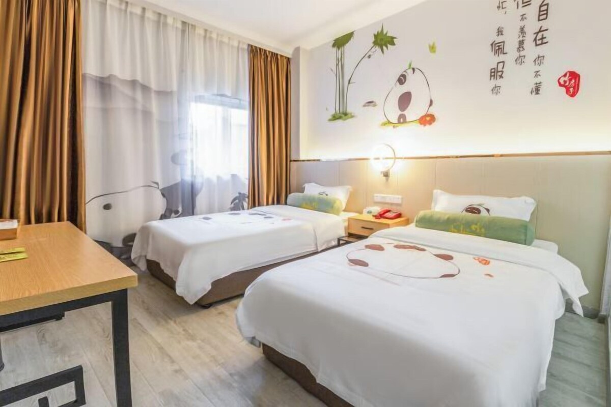 A hotel room with two beds, a wooden table, a desk, and a wall with decorative elements.