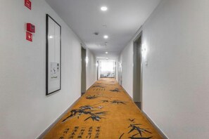 A hotel corridor with a carpeted floor, framed artwork on the walls, and doors leading to rooms. - Zhufangzi Cinema Hotel (Anyue Beimenkou) (Anyue)