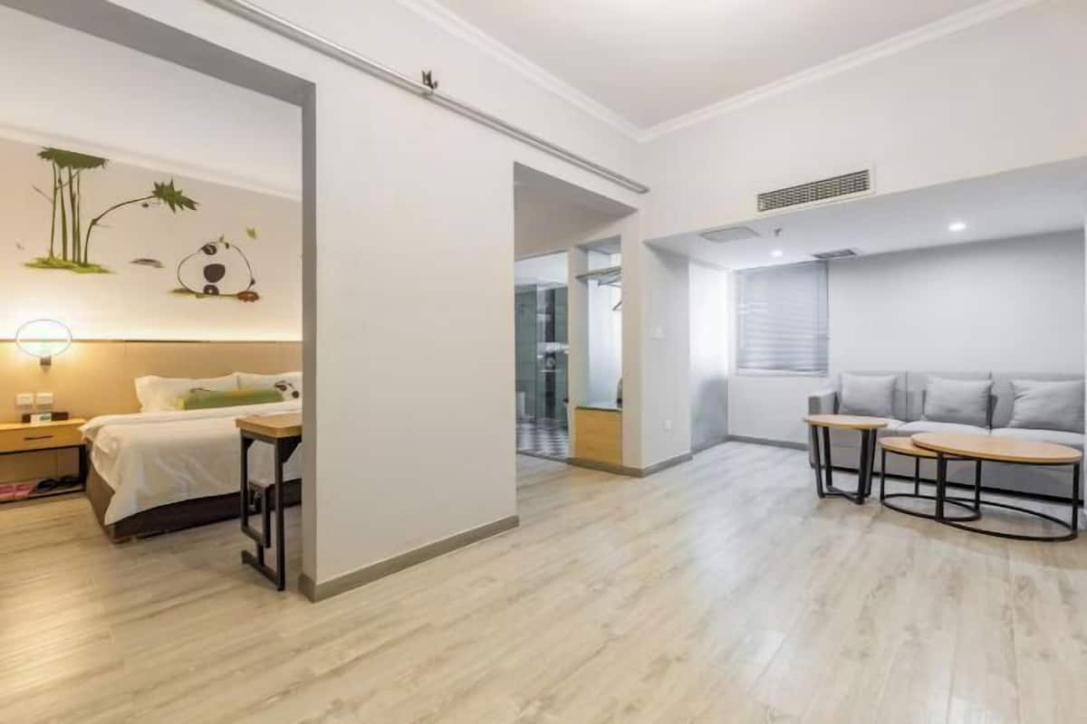 Una habitación de hotel moderna con cama, mesita de noche y un conjunto de sofás.