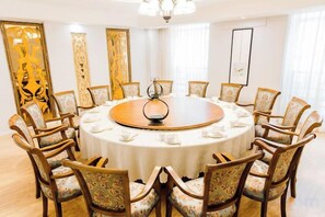 Ein runder Tisch mit Stühlen, einer Kristallleuchter und einer weißen Tischdecke.