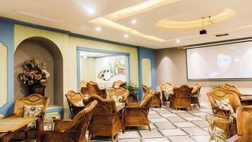 A conference room with wicker furniture, a large screen, and a projector.