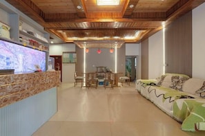 A reception area with a wooden ceiling, a reception desk, a sofa, and a dining table.