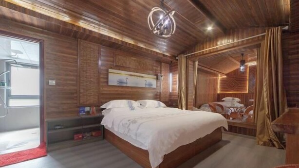 A wooden-paneled bedroom with a bed, a nightstand, and a wall-mounted light fixture. - Xiaoxi Hostel (Zhangjiajie)
