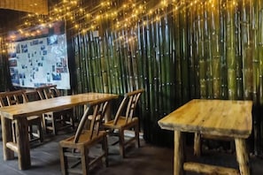 A restaurant interior with bamboo walls, wooden tables, and chairs. - Xiaoxi Hostel (Zhangjiajie)