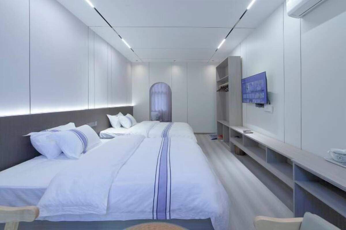 Een moderne hotelkamer met een groot bed, nachtkastjes, een televisie en een kledingkast.