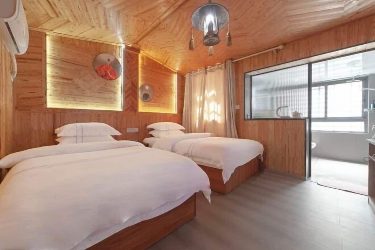Een houten kamer in blokhutstijl met twee bedden, een groot raam en een plafondlamp.
