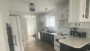 Una cocina moderna con armarios blancos, encimera negra y suelo de madera.