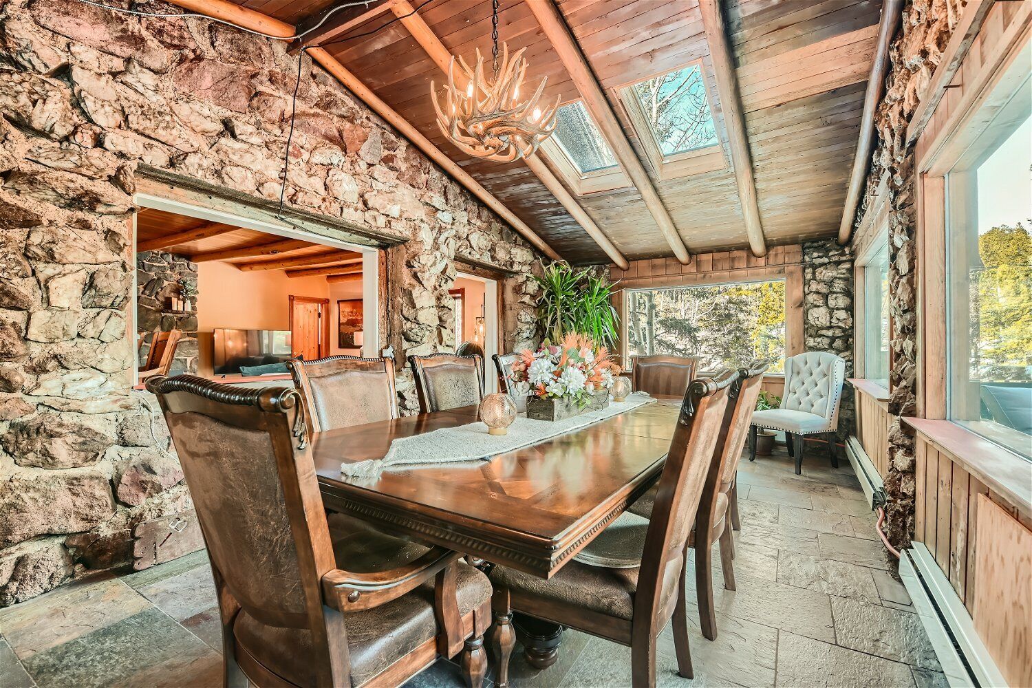 Un coin repas au style rustique, avec un mur en pierre, un plafond en bois et un lustre.