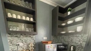 Una cocina con armarios grises, un refrigerador negro y un salpicadero de mármol.