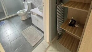 Un baño con inodoro, lavabo y zona de ducha.