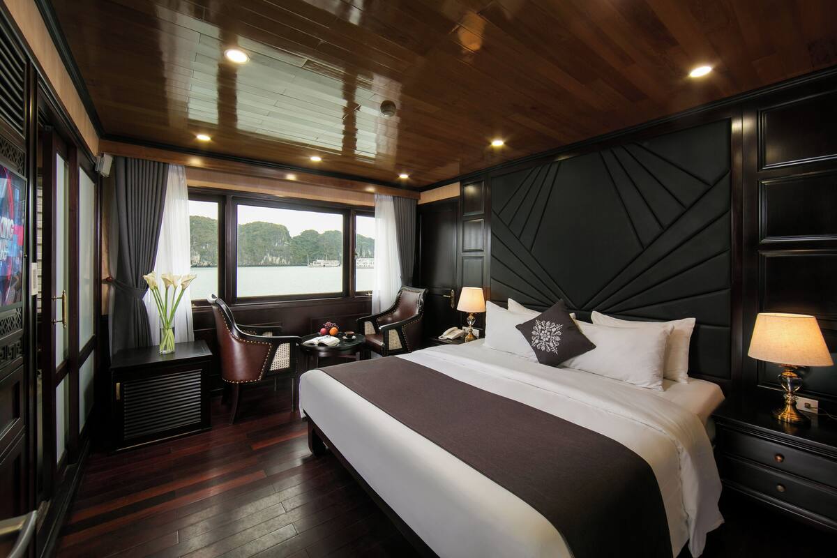 A hotel room with a large bed, a desk, a chair, and a view of the water.