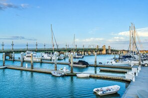 Un puerto deportivo con varios muelles, barcos y un puente al fondo.