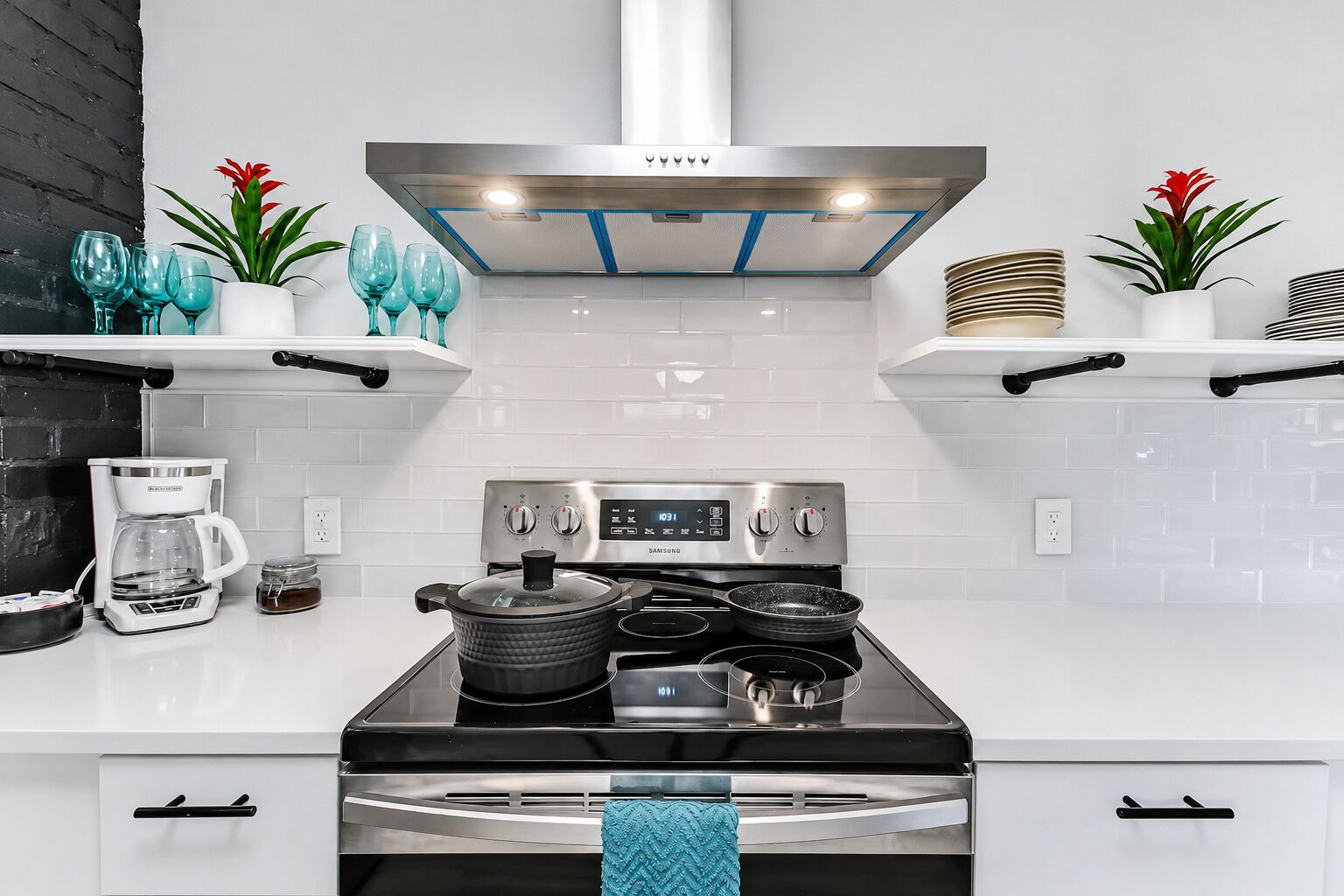 A modern kitchen with a stainless steel range, a coffee maker, and decorative plants.