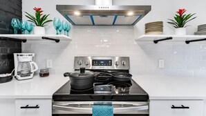 A modern kitchen with a stainless steel range, a coffee maker, and decorative plants.