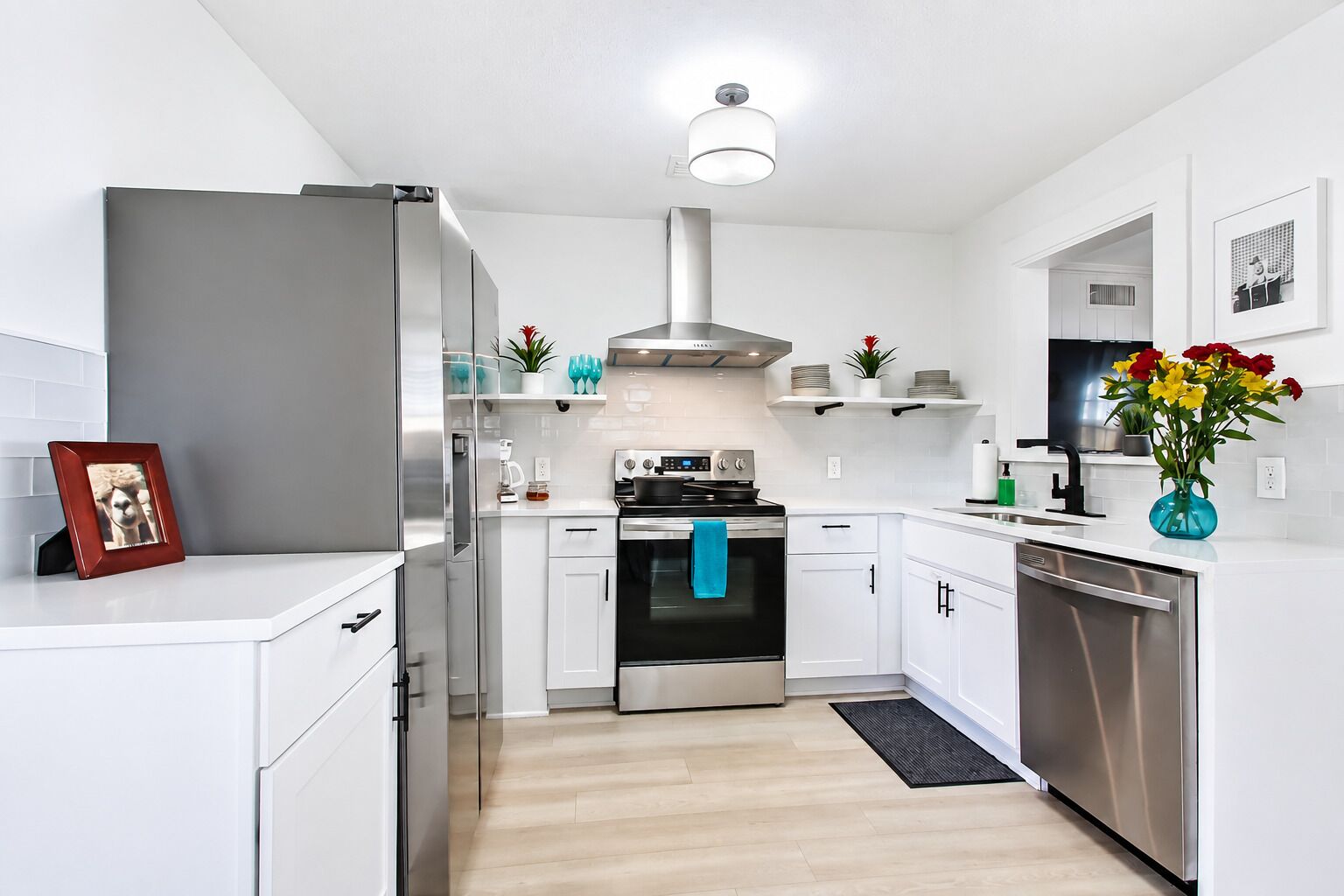 Une cuisine moderne avec des meubles blancs, des appareils en acier inoxydable et un îlot central.