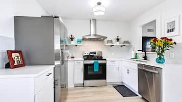 Une cuisine moderne avec des meubles blancs, des appareils en acier inoxydable et un îlot central.