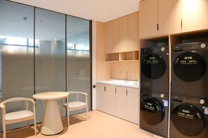 A compact kitchen with a sink, cabinets, and a small table with chairs. - Longji International Hotel (Longsheng)