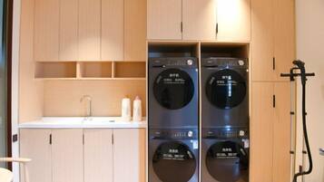 A laundry room with two stacked washing machines and a sink.