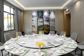 A conference room with a round table set for a meeting, equipped with chairs, plates, cups, and cutlery. - Longji International Hotel (Longsheng)