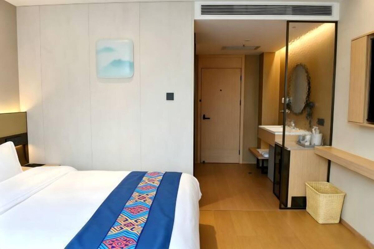 Una habitación de hotel con una cama, un baño con espejo y un pequeño pasillo.