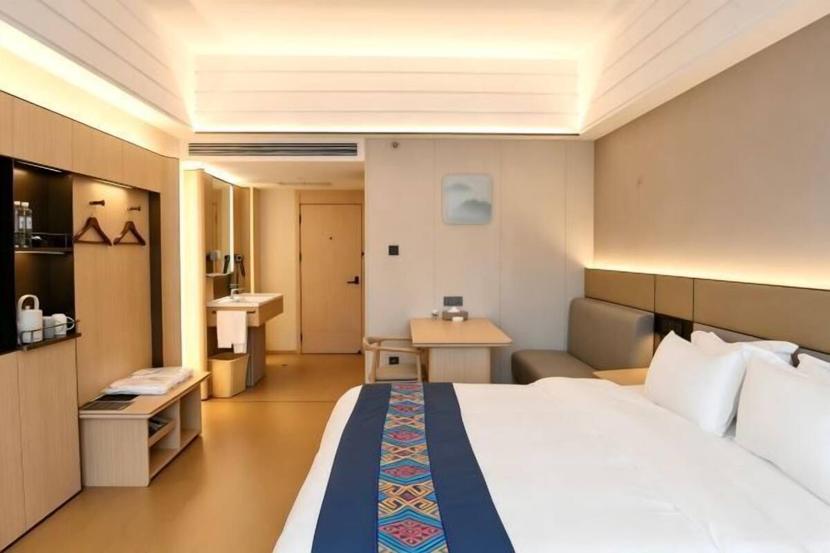 Una habitación de hotel con cama, escritorio, silla, armario y baño.