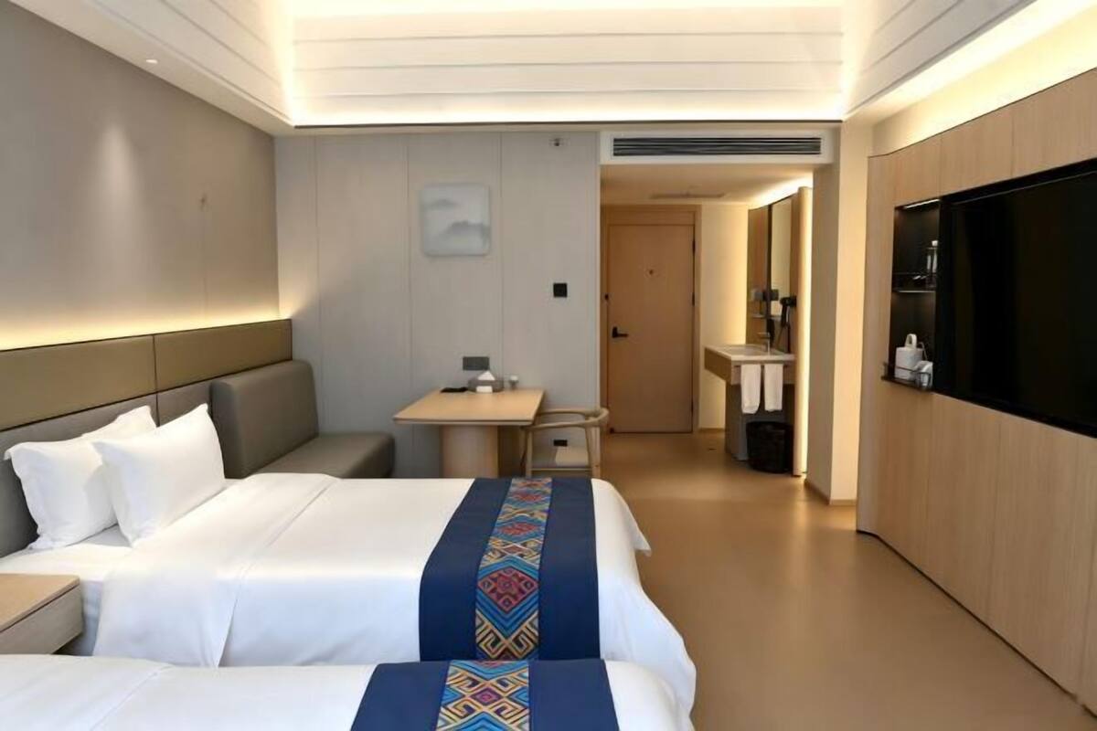 Una habitación de hotel con cama, escritorio, televisión y baño.