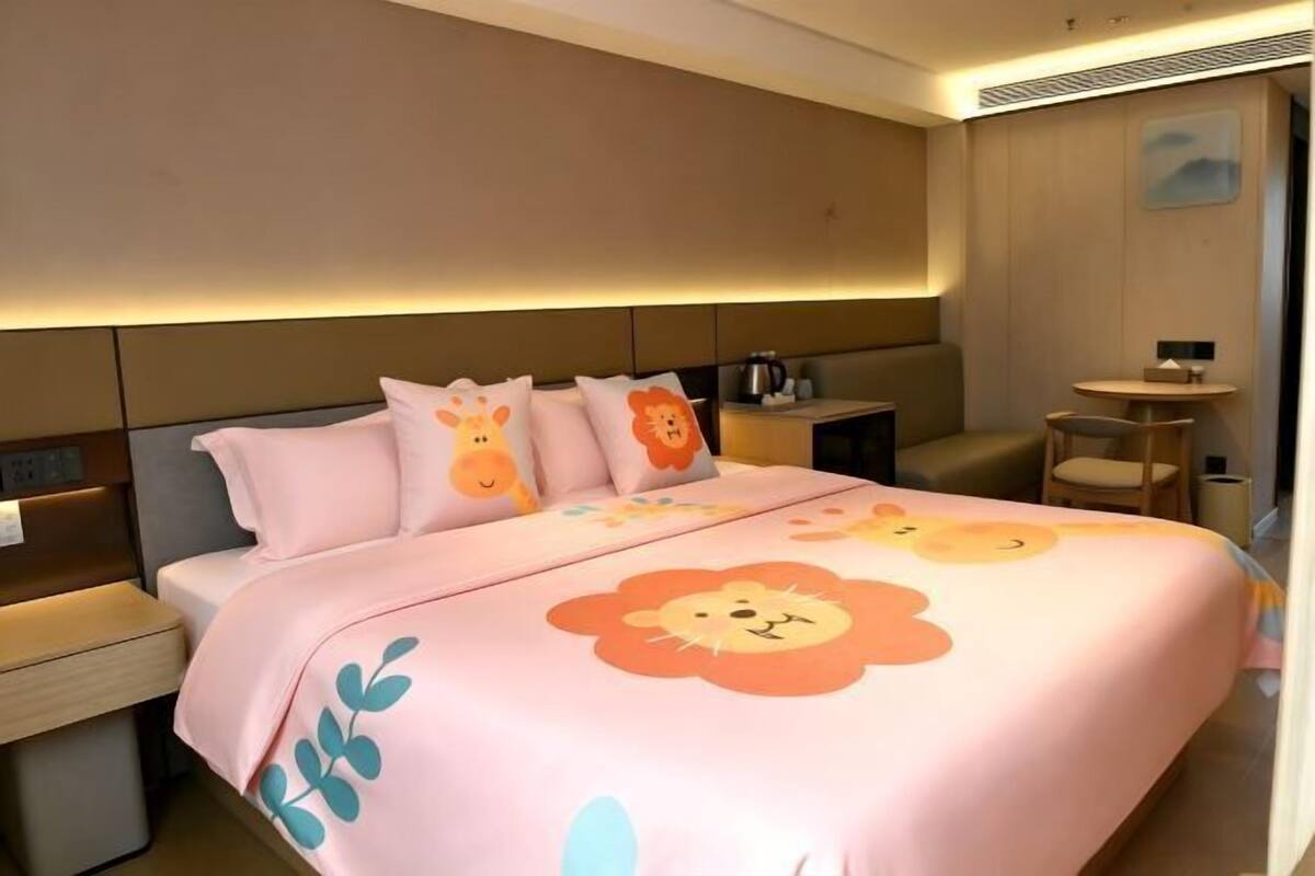 Una habitación de hotel con cama, mesitas de noche, una pequeña mesa y una silla.