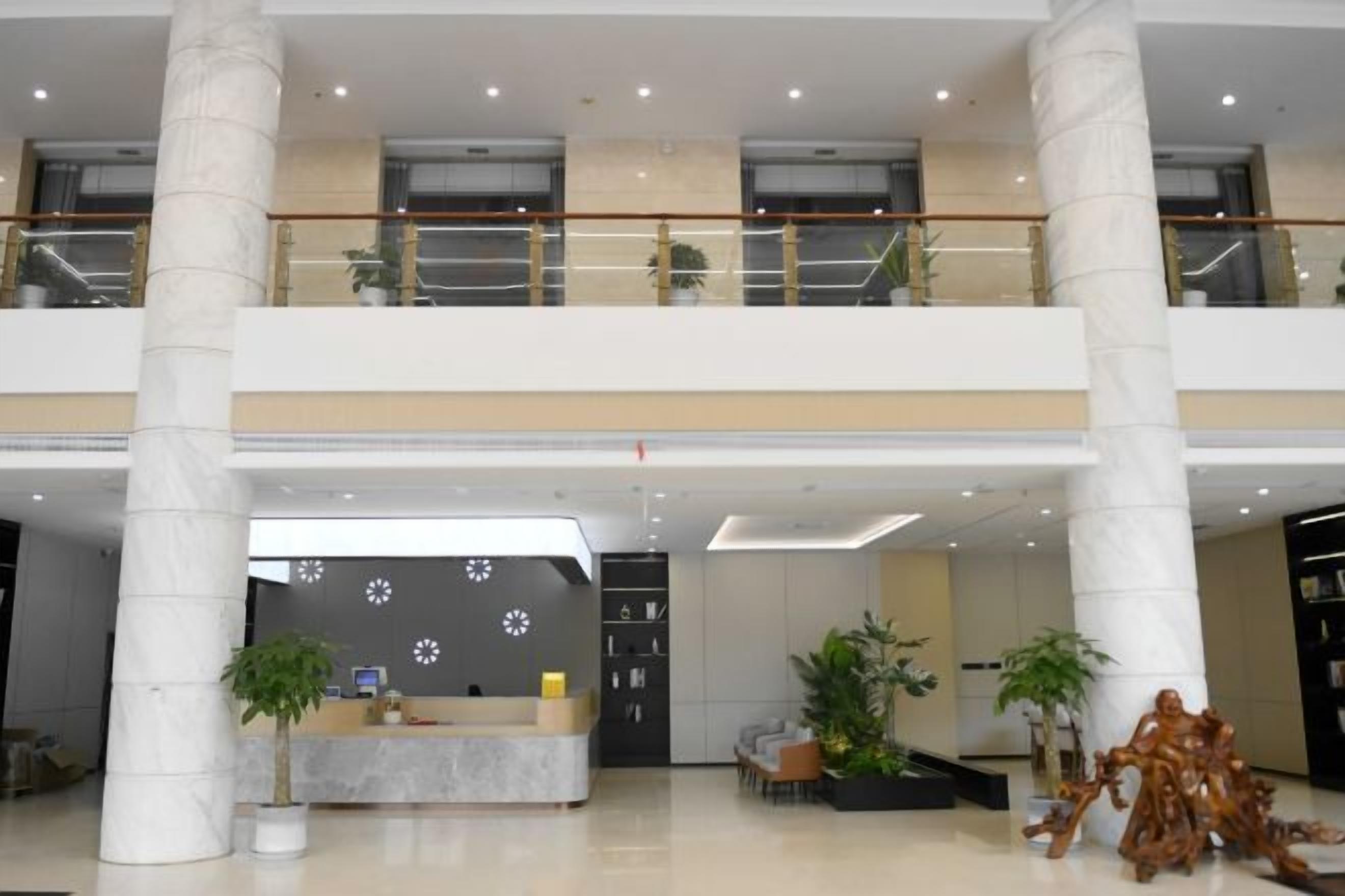 Eine geräumige Lobby mit einer Rezeption, zwei Etagen und einer Treppe.
