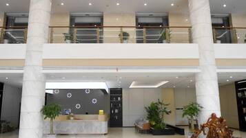 Eine geräumige Lobby mit einer Rezeption, zwei Etagen und einer Treppe.