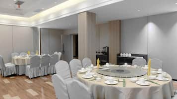 A conference room with round tables, white chairs, and a central table with a circular arrangement.