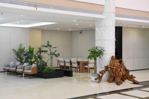 A lobby with seating, a large pillar, and a decorative wooden sculpture. - Longji International Hotel (Longsheng)