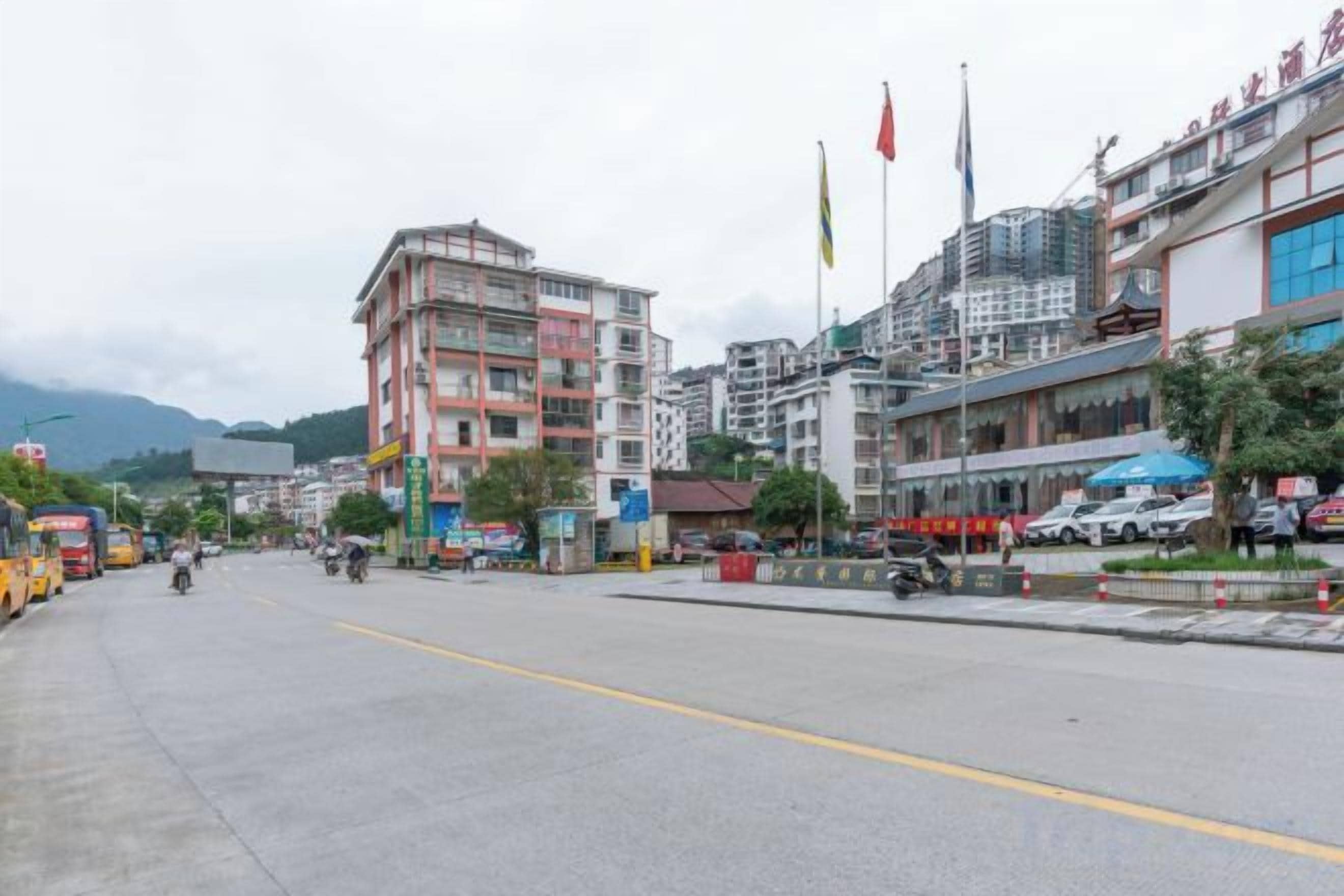 A wide street with buildings, flags, and a clear sky.