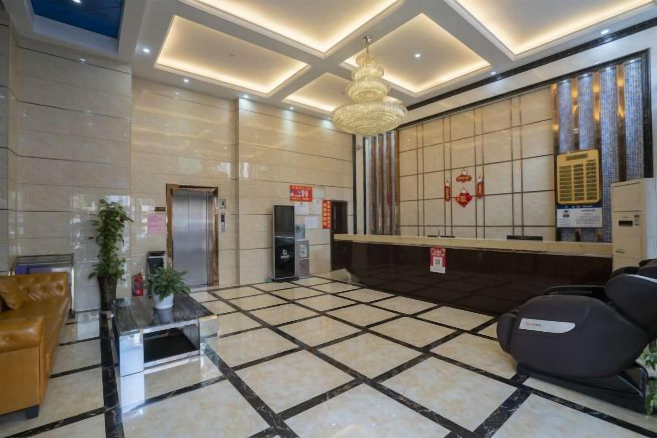 A hotel lobby with a reception desk, a waiting area with chairs, a reception desk, a staircase, and a wall-mounted air conditioning unit.