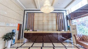 A reception area with a reception desk, a chandelier, a potted plant, and a leather couch. - Kaili Shangjie Hotel (International Trade Shopping Center) (Kaili)