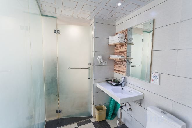 A modern bathroom with a glass shower enclosure, a white sink, and a mirror above it.
