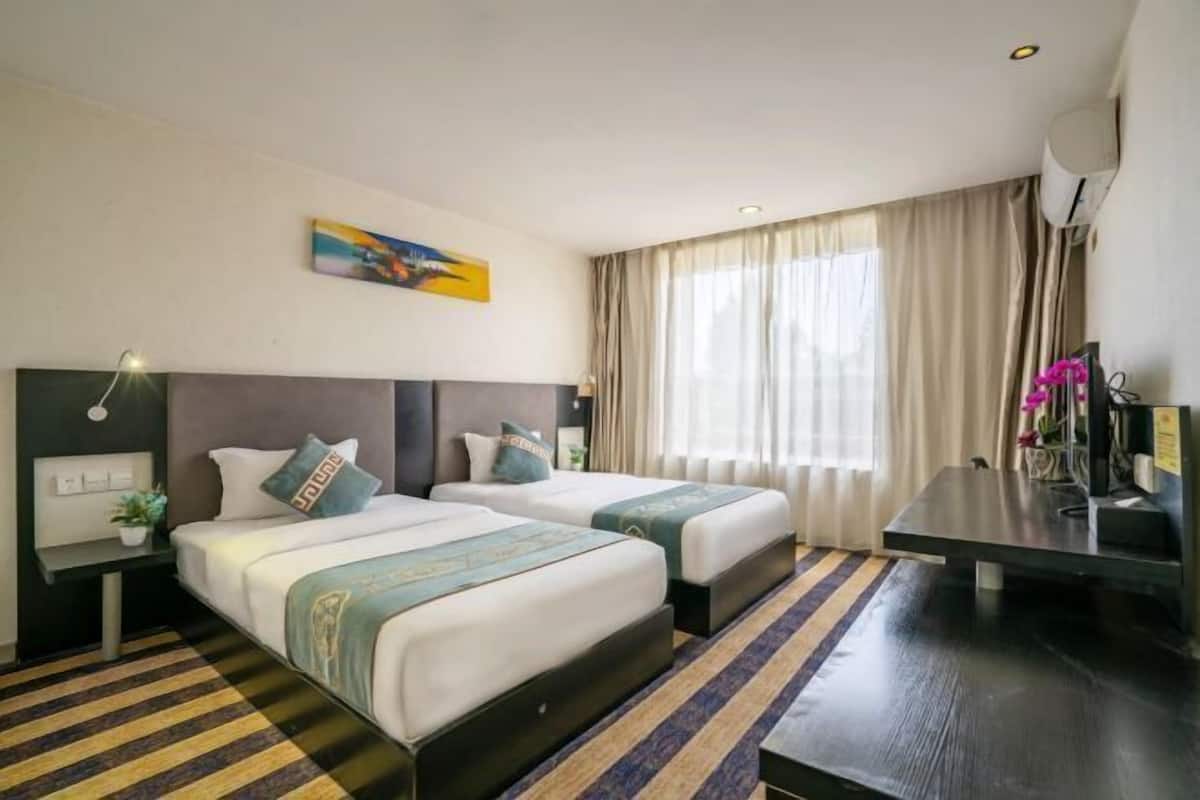 A hotel room with two beds, a desk, a chair, a TV, and a painting on the wall.