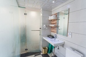 A modern bathroom with a glass shower enclosure, a white sink, and a mirror above it. - Kaili Shangjie Hotel (International Trade Shopping Center) (Kaili)