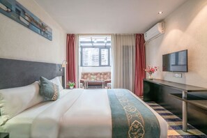 A hotel room with a bed, a TV, a desk, a sofa, and a window with curtains. - Kaili Shangjie Hotel (International Trade Shopping Center) (Kaili)